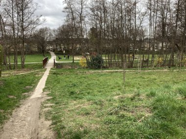 Dar bir yolu ve bulutlu bir günde köprüsü olan bir park.