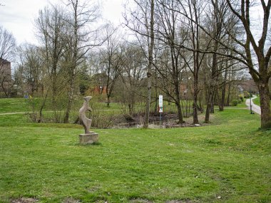 Ağaçların arka planında taze yeşil çimlerle kaplı bir şehir parkı.