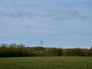 A natural view of powerline across greenfields in the countryside