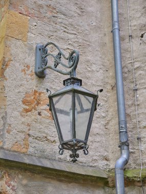 Gündüz vakti grunge duvarında klasik bir sokak lambasının dikey görüntüsü.