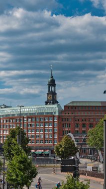 Hamburg 'da arka planda kilise olan kırmızı bir binanın dikey görüntüsü.