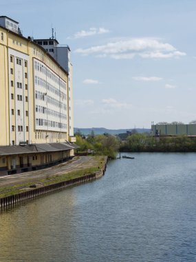 Hameln şehrindeki Weser Nehri 'nin dikey görüntüsü. Parlak gökyüzünün altında güzel binalar var.