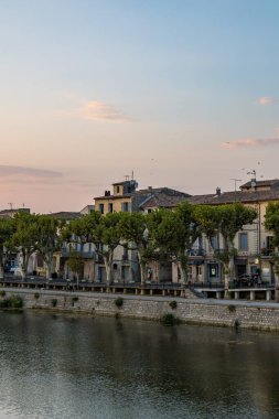 Buildings along the Allee Frederic Mistral in Sommieres, on the banks of the Vidourle River, at sunset