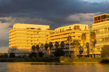 Residential buildings around Bassin Jacques Coeur in Montpellier illuminated by sunset clipart