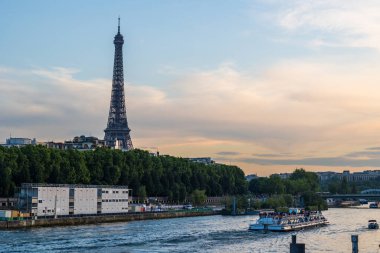 Günbatımında Eyfel Kulesi Seine nehrinin önünde, tekne ve mavnalarla.