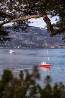 Saint-Jean-Cap-Ferrat 'taki Anse de la Scaletta' da kırmızı gövdeli küçük bir yelkenli.