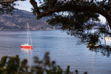 Saint-Jean-Cap-Ferrat 'taki Anse de la Scaletta' da kırmızı gövdeli küçük bir yelkenli.