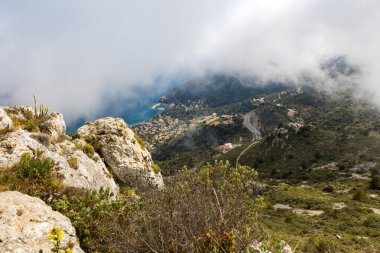 Eze-Bord-de-Mer, villaları ve kumsalı Mont Bastide 'in tepesinden alçak bulutların arasından geçiyor.