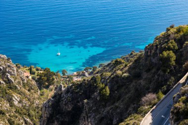 Mont Bastide yamaçlarından Eze-Bord-de-Mer 'in berrak sularında demirli küçük yelkenli.