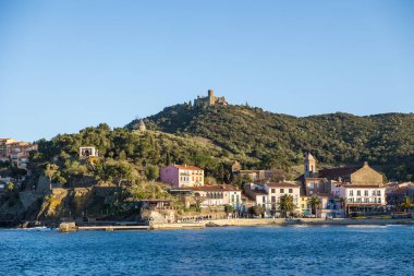 Fort Saint-Elme ve Moulin de la Cortina Collioure 'daki Port d' Avall sahilinin yukarısında fırtınalı bir havada gün batımında