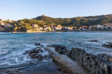 Fort Saint-Elme ve Moulin de la Cortina Collioure 'daki Port d' Avall sahilinin yukarısında fırtınalı bir havada gün batımında