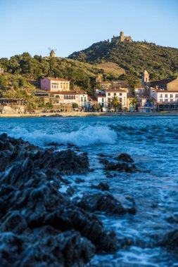Fort Saint-Elme ve Moulin de la Cortina Collioure 'daki Port d' Avall sahilinin yukarısında fırtınalı bir havada gün batımında