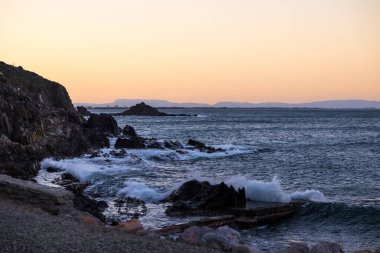 Collioure 'un eteğindeki kayalara vuran dalgaların üzerinde gün batımı