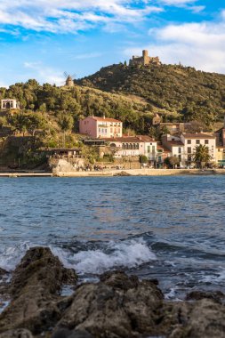 Fort Saint-Elme ve Moulin de la Cortina Collioure 'daki Port d' Avall plajının yukarısında gün batımında.