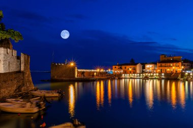 Yunanistan 'ın Nafpaktos limanında dolunaya karşı suyu yansıtan ışıklar.