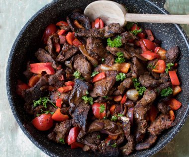 Kızartma tavasında sebzeyle kızartılmış biftek.