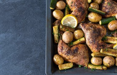 Yukarıdan izole edilmiş koyu arkaplandaki pişirme tepsisindeki sağlıklı yiyecekler.