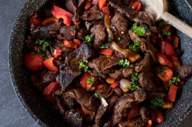 Kızarmış bifteği tavada sebzeyle karıştır. Çan biberi, soğan, sarımsak, domates, biber ve bitkilerle pişirilmiş.. 