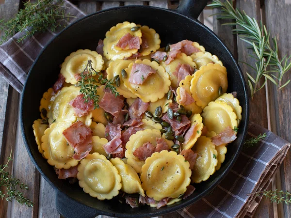 意大利面里塞满了蘑菇 用火腿 香草和黄油烹调 顶部的烤南瓜种子 并在一个乡村锅中的木制背景 — 图库照片