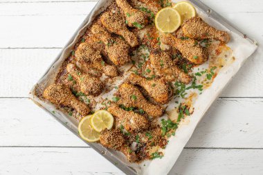 Harissa makarna ve susam tohumu soslu ev yapımı baharatlı tavuk budu. Beyaz ahşap arka planda izole edilmiş fırın tepsisinde yemeye hazır. Düz yatıyordu