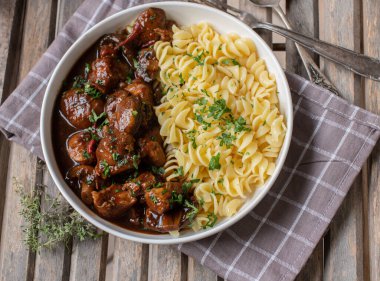 Tabağında makarna olan kümes hayvanı kebabı. Az yağlı hindi göğsüyle pişirilmiş ve yukarıdan ahşap arka planda yenmeye hazır.