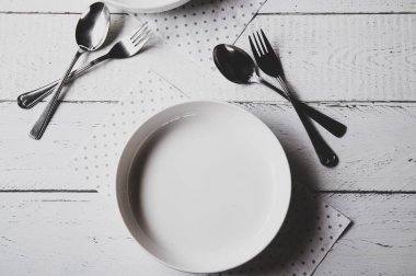 Beyaz plaka, çatal ve kaşıkla soyut, beyaz, mat arkaplan. Düz yatıyordu