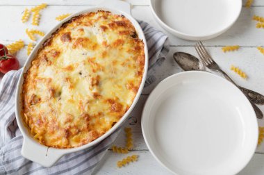 Fusilli erişte, bolonez ve beşamel soslu makarna güveci. Beyaz arka planda mozzarella peyniri kabuğuyla kaplı.