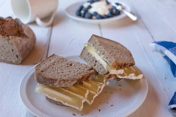 Sourdough bread sandwich with low fat and high protein quark cheese. Served with a fresh yogurt and berries on white table