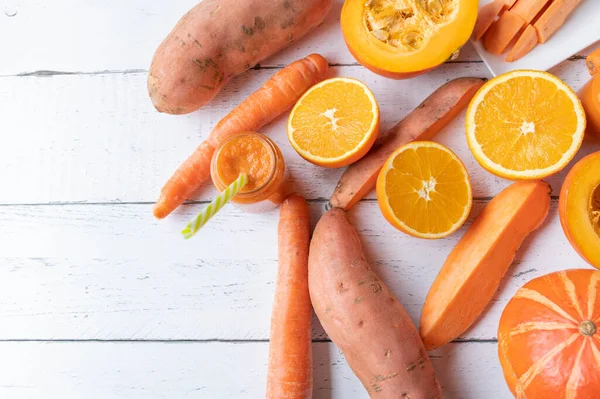 Orange colored  vegetables and fruits on white background. Flat lay with space for text