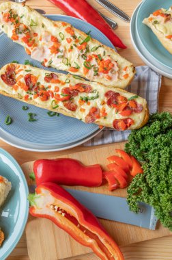 Baked baguette sandwiches with salami, ham and cheese. Topped with red peppers and chives