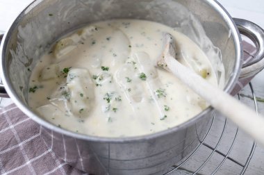 Beşamel soslu Kohlrabi, tahta kaşıkla tencerede..