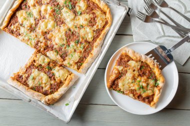 Biftekli, peynirli, domatesli, soğanlı, biberli ve kabuklu pizza.