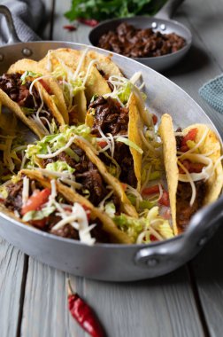 Yavaş pişmiş Meksika bifteği, peynir, domates ve marullu tacolar.