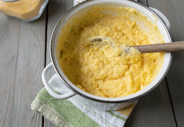 stock image Traditional and homemade creamy polenta. Cooked with broth, milk and parmesan cheese. Served hot and ready to eat in a pot with wooden spoon from above.