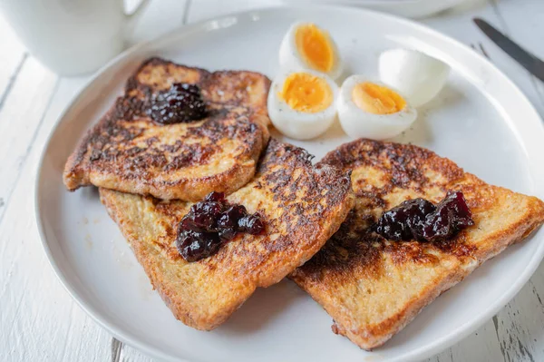 Whole grain french toast with blueberry jam and boiled eggs on a plate for breakfast