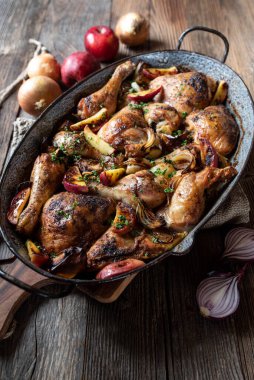 Ahşap masada izole edilmiş eski moda bir tavada soğanlı ve elmalı haşlanmış tavuk.