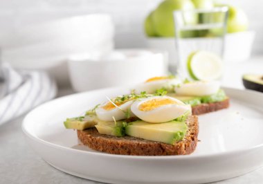 Avokado yumurtalı sandviç ve tabakta çavdar ekmeği.