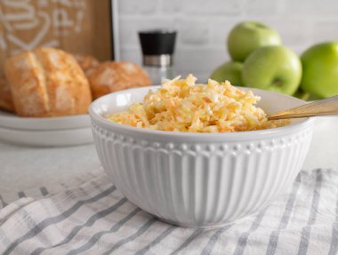 Amerikan lahana salatası, beyaz lahana ve havuçlar mutfak masasında, arka planda çöreklerle birlikte.