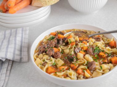 Etli erişte çorbası ve tabakta kök sebze.