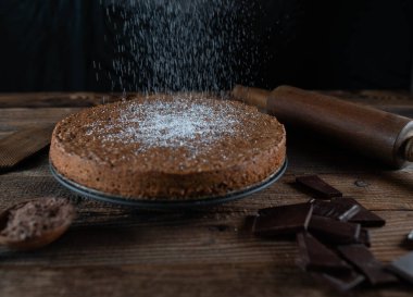 Fırında pişmiş çikolatalı kekin üzerine pudra şekeri serpiyorum. Geleneksel İtalyan torta caprese ile badem.