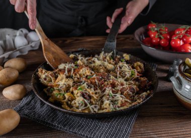 Çiftçilerin kahvaltısında kızarmış patates, pastırma, yumurta, soğan ve peynir var. Ahşap bir masada, kırsal bir demir tavada servis edilmiş..