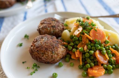 Domuz köftesi, tereyağlı bezelye, havuç ve haşlanmış patates. Geleneksel Alman mutfağı.