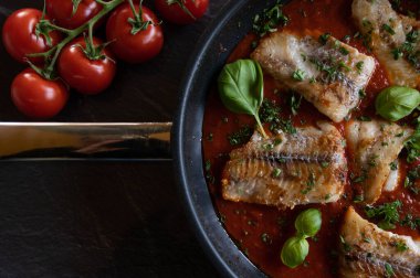 Kızarmış tavada baharatlı domates soslu kızarmış balık.