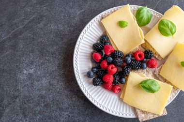 Az karbonhidratlı gevrek, eski gouda peyniri ve koyu arkaplanda izole edilmiş taze böğürtlenli sağlıklı bir kahvaltı. Üst görünüm