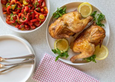 Fırın, yarım tavuk ve beyaz masada salata. Üst görünüm