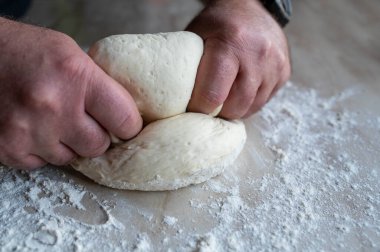 Un kaplı mutfak tezgahında taze hamur yoğuran erkek eller.