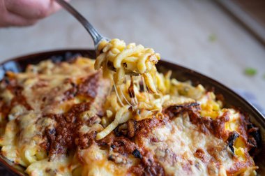 Fırında pişmiş peynirli spaetzle ve kavrulmuş soğan. Sıcak servis edildi ve çatalda yemeye hazır..