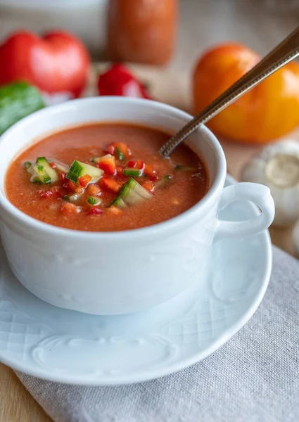 Beyaz bir çorba bardağında kaşık içinde gazpacho endalusia. Çiğ sebzeli lezzetli ve sağlıklı sebze çorbası..