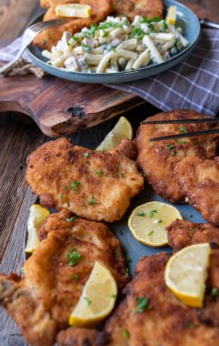 Tavada kızarmış pirzola ve ahşap masada geleneksel erişte salatası.