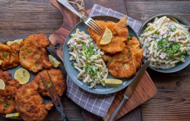 Geleneksel Alman yemeği, ekmek arası pirzola ve ahşap masa arkasında makarna salatası. Üst görünüm